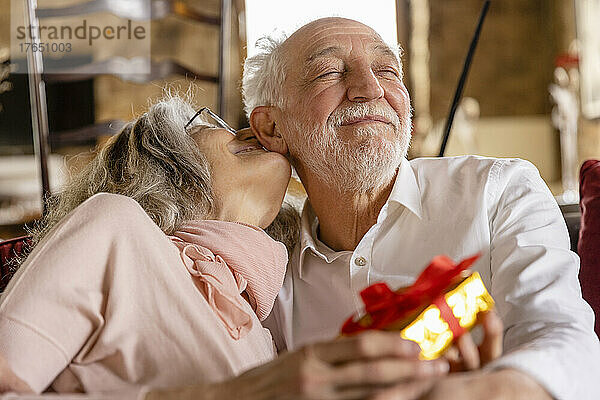 Smiling woman embracing man sitting with eyes closed at boutique hotel
