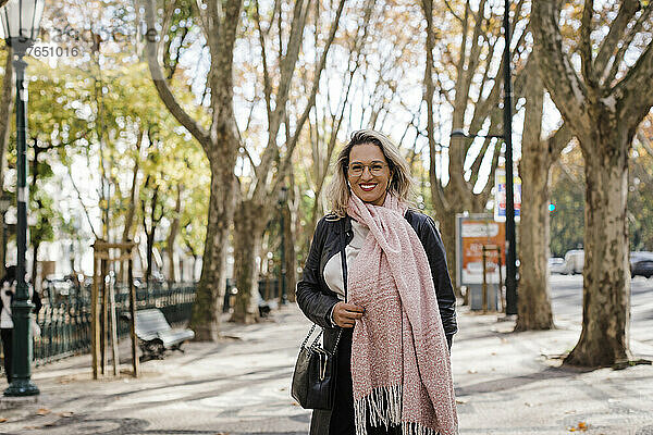 Lächelnde Frau mit Schal steht auf Fußweg