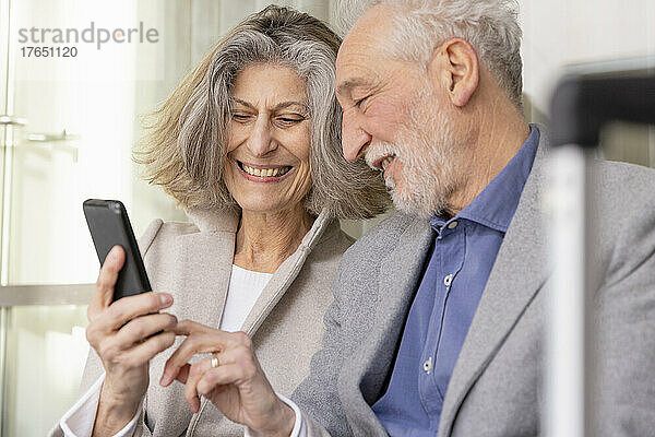 Glückliche ältere Frau teilt Smartphone mit Mann