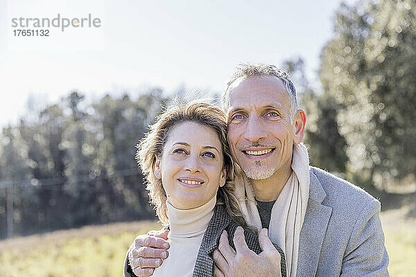 Smiling mature couple day dreaming on sunny day