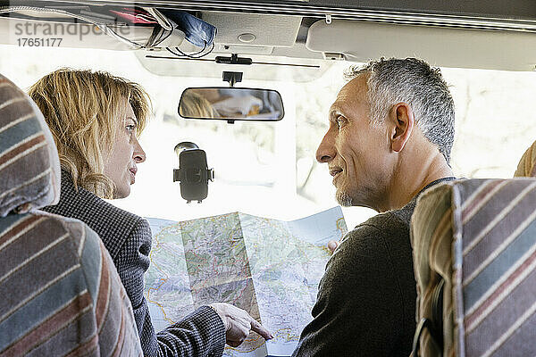 Mature couple discussing over map in camper van
