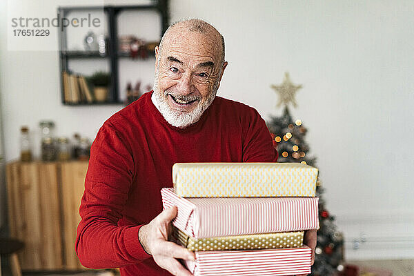 Lächelnder älterer Mann  der zu Hause Geschenkboxen verteilt