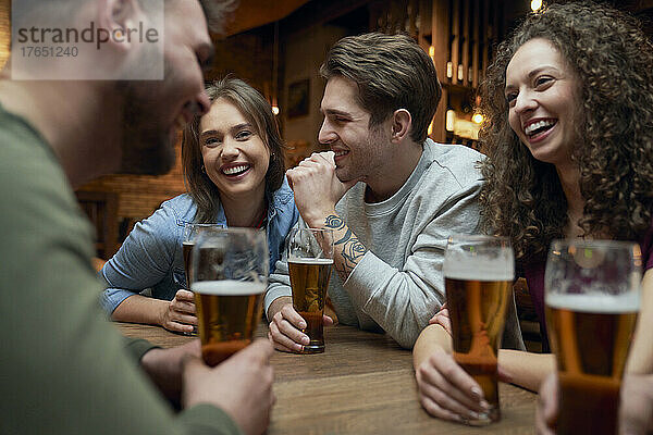 Gruppe glücklicher Freunde  die Bier trinken und sich in einer Kneipe unterhalten