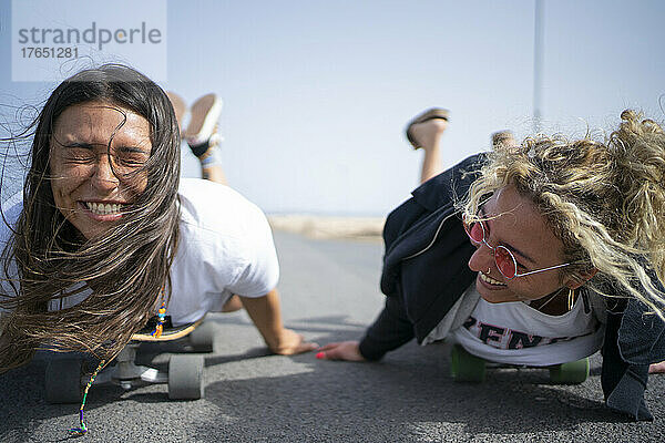 Freunde haben Spaß  indem sie vorne auf dem Skateboard liegen
