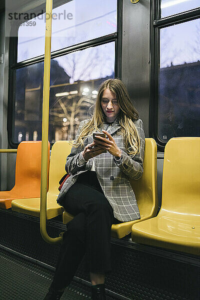 Junge Frau benutzt Mobiltelefon in der Straßenbahn