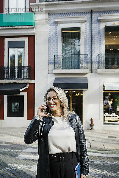 Lächelnde Frau  die auf der Straße über ihr Mobiltelefon spricht