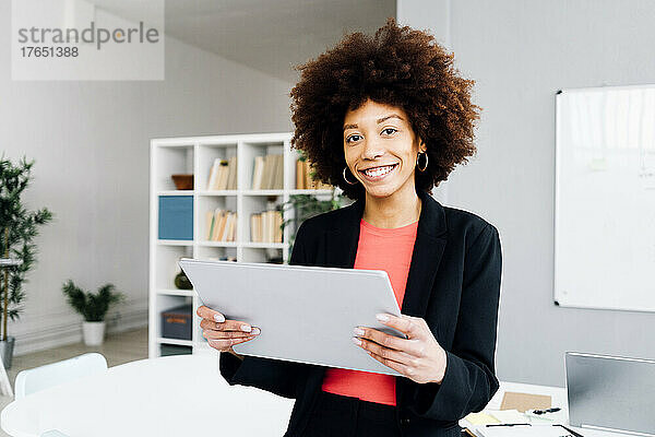 Glückliche Geschäftsfrau mit Tablet-PC im Büro