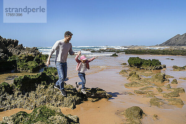 Glücklicher Vater und Tochter  die Spaß am felsigen Strand haben