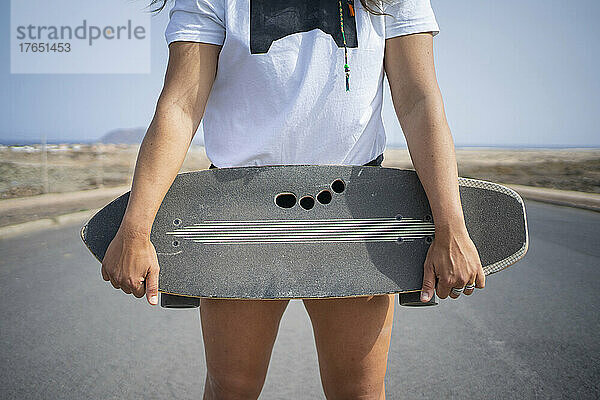 Frau hält Skateboard an sonnigem Tag