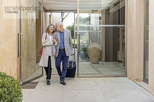 Lächelndes älteres Paar geht in der Lobby eines Boutique-Hotels spazieren