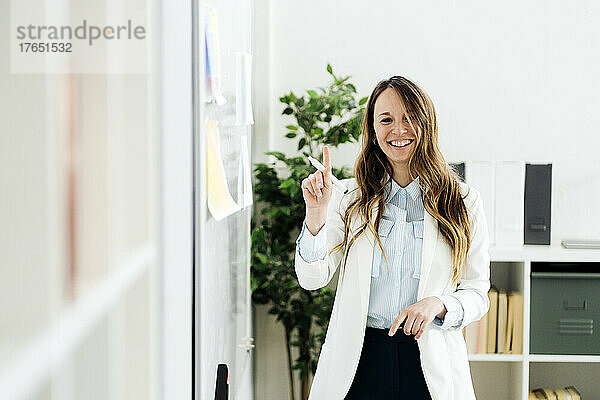 Lächelnde Geschäftsfrau mit Filzstift im Büro