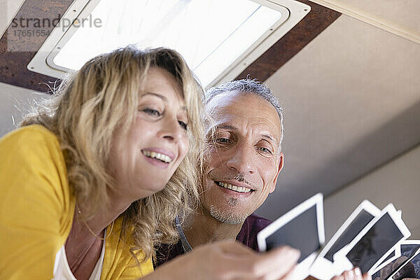 Smiling mature couple looking at photograph in camper van