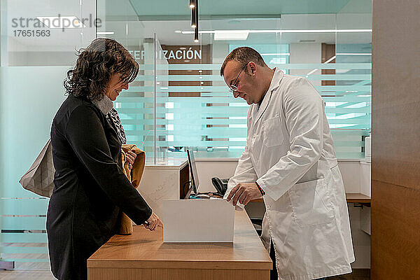 Arzt zeigt dem Patienten an der Rezeption im Krankenhaus den medizinischen Bericht