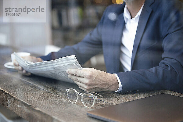 Geschäftsmann mit Zeitung sitzt am Tisch im Café