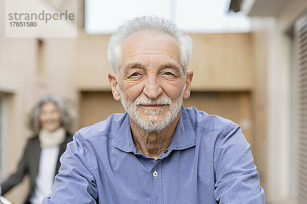 Lächelnder älterer Mann mit weißem Haar vor einer Frau