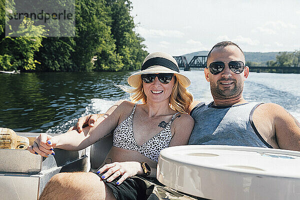 Ein Paar entspannt sich an einem sonnigen Tag mit umeinander geschlungenen Armen im Boot