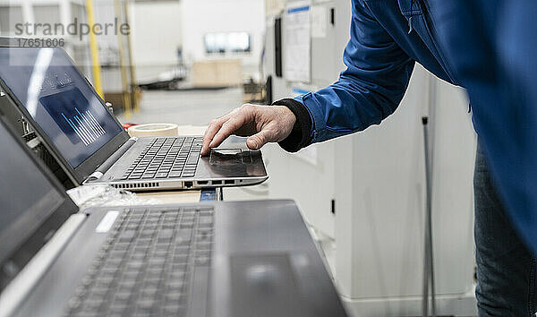 Hand eines Technikers mit Laptop in der Fabrik