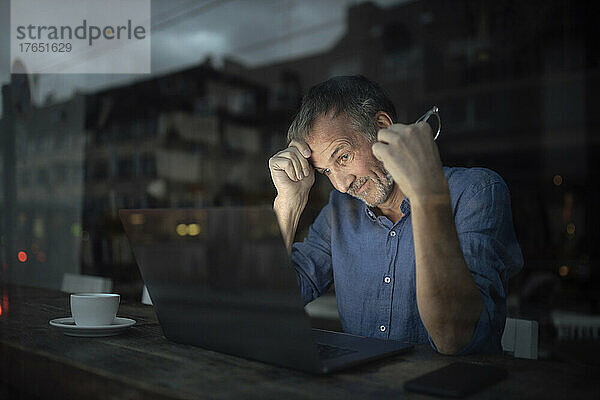 Geschäftsmann mit Laptop arbeitet nachts im Café