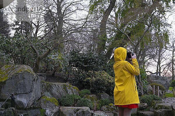 Frau im gelben Regenmantel fotografiert im Wald