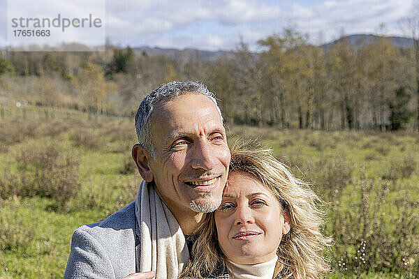 Smiling mature couple day dreaming together on sunny day