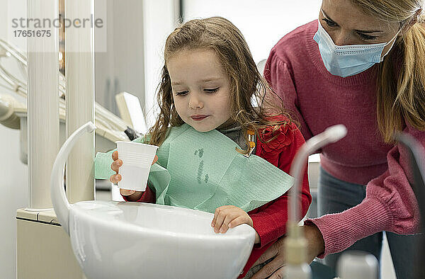 Nettes kleines Mädchen gurgelt in der Zahnklinik