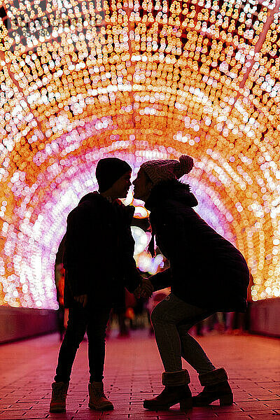 Mother embracing son in tunnel with Christmas lights