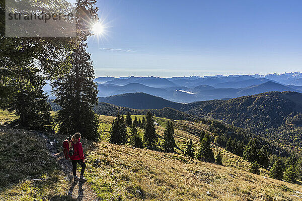 Wanderin bewundert die Bayerischen Voralpen bei nebligem Sonnenaufgang