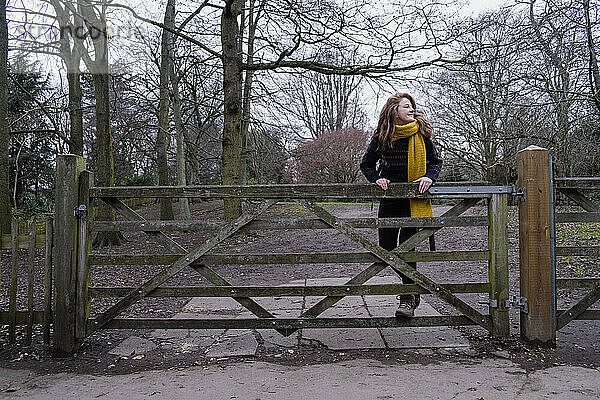 Glückliche Frau steht am Tor im Wald
