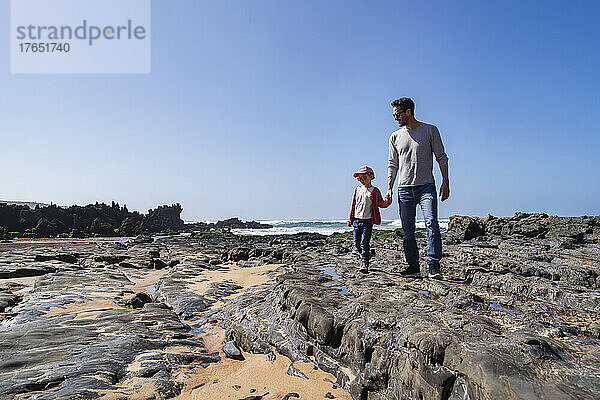Glücklicher Vater und Tochter stehen auf einem Felsen am Strand