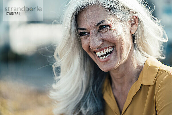 Geschäftsfrau mit grauem Haar lacht an sonnigem Tag