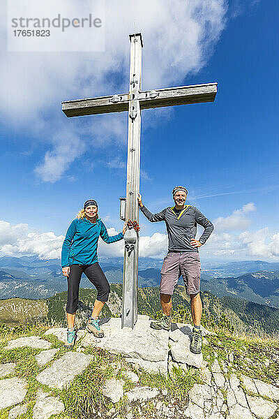 Zwei Wanderer posieren am Gipfelkreuz des Demeljochs