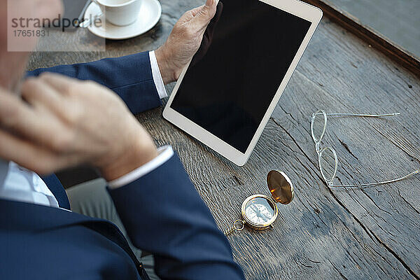 Geschäftsmann mit Navigationskompass und Brille nutzt Tablet-PC im Café