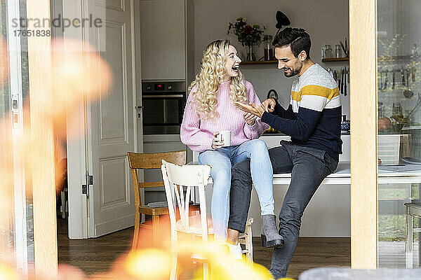 Playful couple sitting on table at home