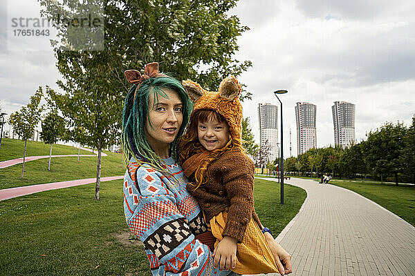 Mutter trägt Tochter auf Fußweg im öffentlichen Park