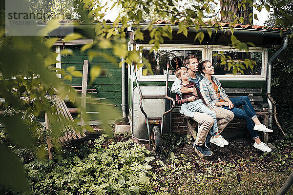 Mann mit Frau und Sohn sitzen auf Bank im Hinterhof