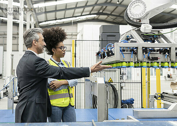 Geschäftsmann diskutiert mit Ingenieur über Roboterarmmaschine in der Fabrik