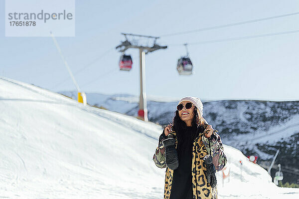 Lächelnde Frau mit Winterhandschuhen  die im Skigebiet genießt