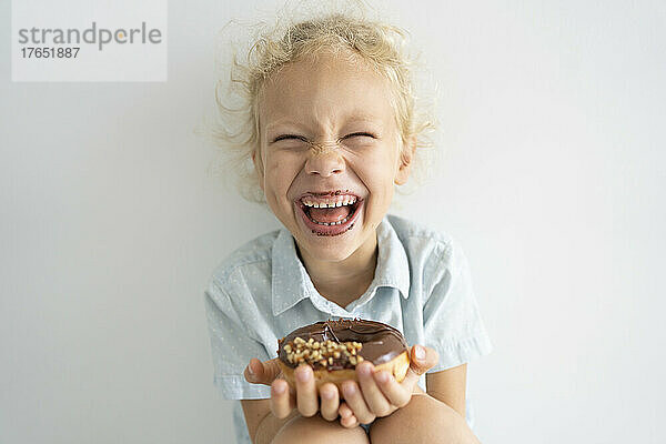 Fröhliches Mädchen hält Donut in der Hand und lacht