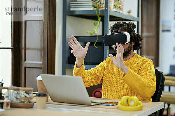 Geschäftsmann mit Laptop und Virtual-Reality-Simulator im Büro