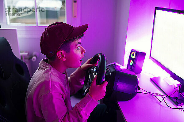 Überraschter Junge  der zu Hause ein Videospiel am Computer spielt