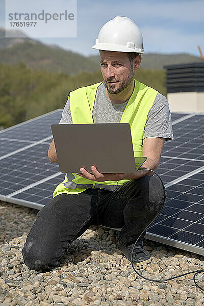 Ingenieur mit Laptop installiert Sonnenkollektoren an einem sonnigen Tag