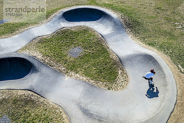 Young woman practicing skateboarding at pump track on sunny day