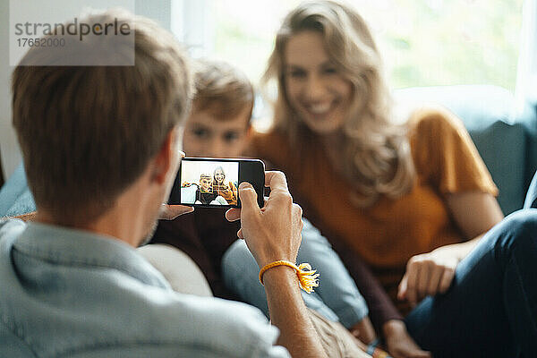 Mann fotografiert Frau und Sohn zu Hause per Smartphone