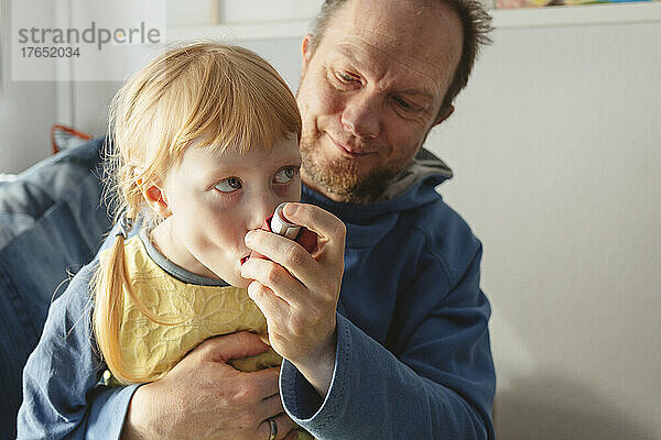 Vater hilft Tochter bei der Anwendung eines Asthmainhalators zu Hause