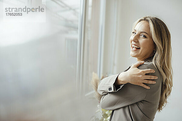 Glückliche Geschäftsfrau umarmt sich im Büro