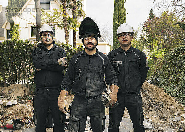 Lächelnde Arbeiter mit Schleifmaschinen und Arbeitswerkzeug auf der Baustelle