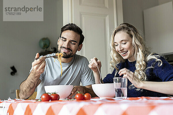 Mann und Frau sitzen zu Hause am Esstisch und essen Essen