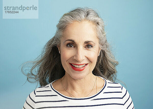 Smiling woman with red lipstick against blue background