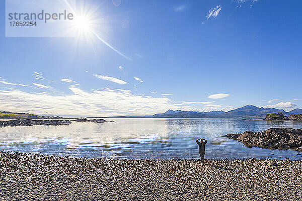 Frau genießt an einem sonnigen Tag die Aussicht auf den Strand