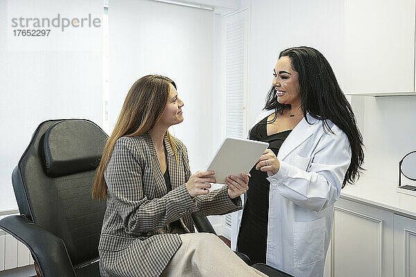 Arzt diskutiert über Tablet-PC mit Patient in der Klinik